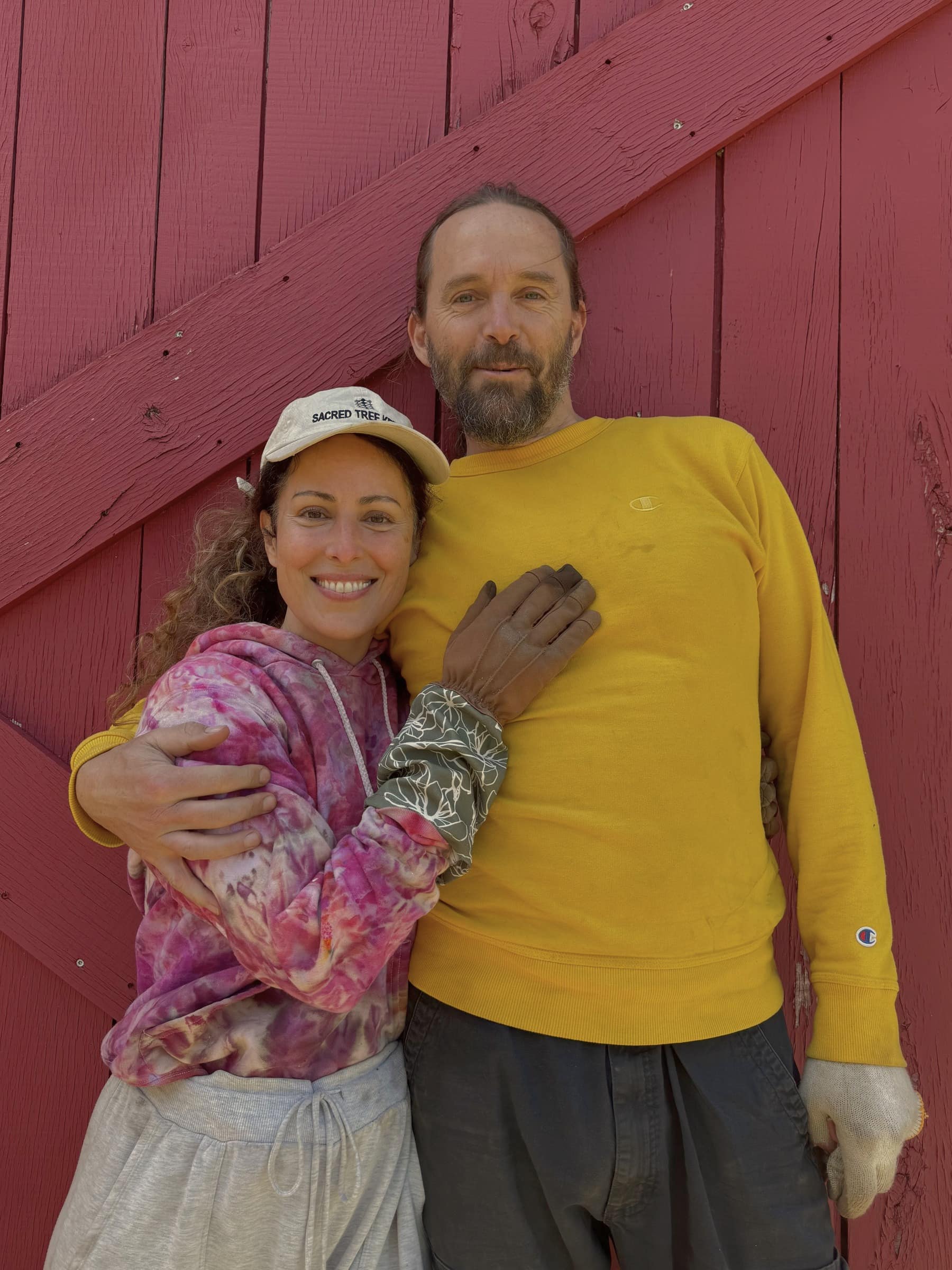 Couple embracing in front of a red wooden barn wall