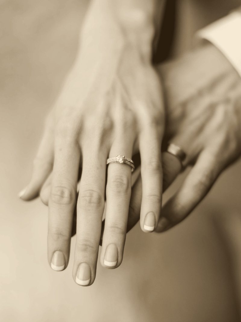 Close-up of a couple's hands together showing their wedding rings