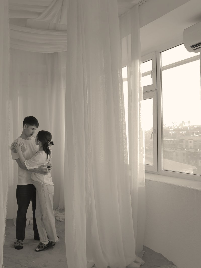 Couple embracing in a bright room with long white curtains