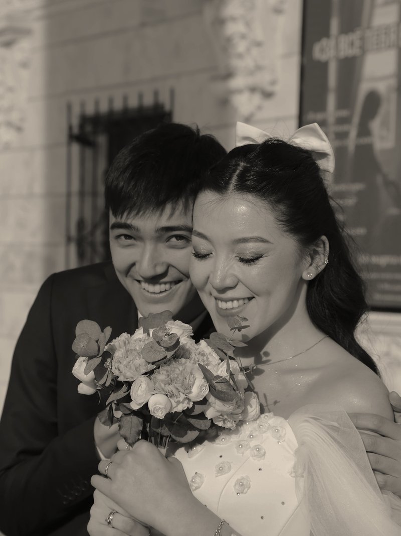 Smiling couple close together holding a bouquet